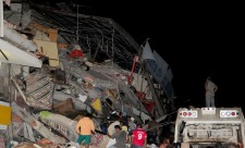 People stand next to the debris of a building after an earthquake struck off the Pacific coast, in Manta, Ecuador, April 16, 2016. REUTERS/Paul Ochoa